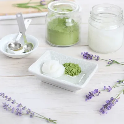 Primo piano di matcha in polvere su piattino bianco, ripreso da vicino per mostrarne consistenza, colore e forma su fondo chiaro o naturale.