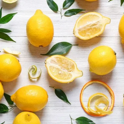 Composizione con limoni interi e tagliati disposti su uno sfondo chiaro, in una fotografia luminosa e pulita.