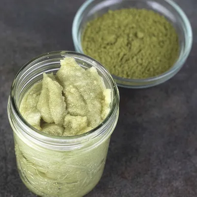 Barattolo di vetro riempito con crema verde al matcha dalla consistenza densa, ripreso in primo piano su sfondo chiaro.