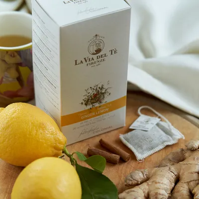 Immagine di scatola bianca di tè con limoni e zenzero, fotografata come prodotto in un set curato con fondo, ingredienti o elementi decorativi coerenti.
