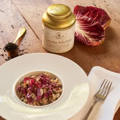 Primo piano di piatto gourmet con fiori e petali, impiattato con cura su un tavolo o sfondo neutro, con ingredienti e decorazioni visibili attorno.
