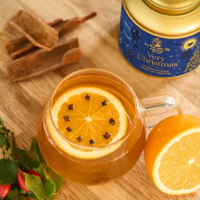 Primo piano di barattolo blu natalizio con bottiglia e zucche, con confezione ben visibile e ingredienti o accessori disposti intorno alla scena.