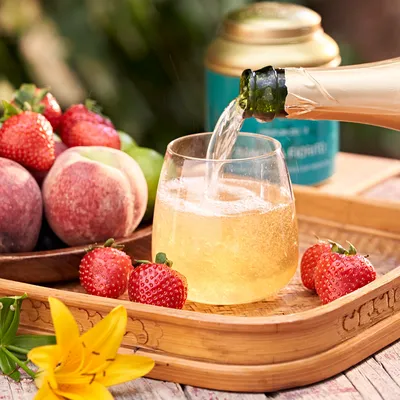 Bevanda alla frutta servita in un bicchiere, con barattolo di tè in primo piano e frutta fresca disposta intorno.