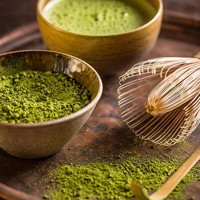 Ciotola with matcha green brillante and frusta of bambù appoggiata next to.