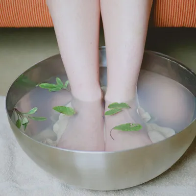 Gambe immerse fino with caviglie in with bacinella metal per foot bath.