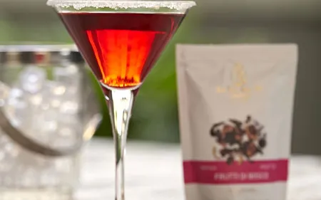 Close-up of red cocktail with package and ingredients.