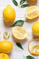 Composition avec citrons interi et tagliati disposés sur un fond clair.