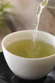 Gros plan de thé versato dans une tasse blanche.