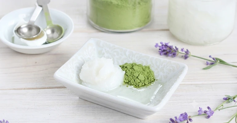 Primo piano di matcha in polvere su piattino bianco, ripreso da vicino per mostrarne consistenza, colore e forma su fondo chiaro o naturale.