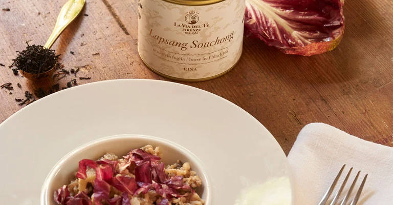 Primo piano di piatto gourmet con fiori e petali, impiattato con cura su un tavolo o sfondo neutro, con ingredienti e decorazioni visibili attorno.