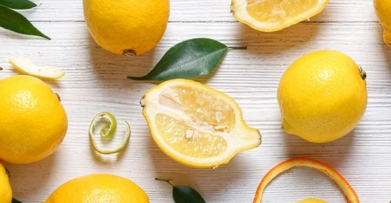 Composition avec citrons interi et tagliati disposés sur un fond clair.