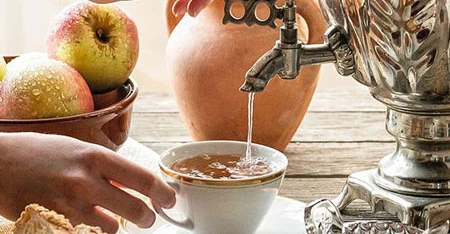 Detail of the hands of with person that prepares il tea using with samovar metal.