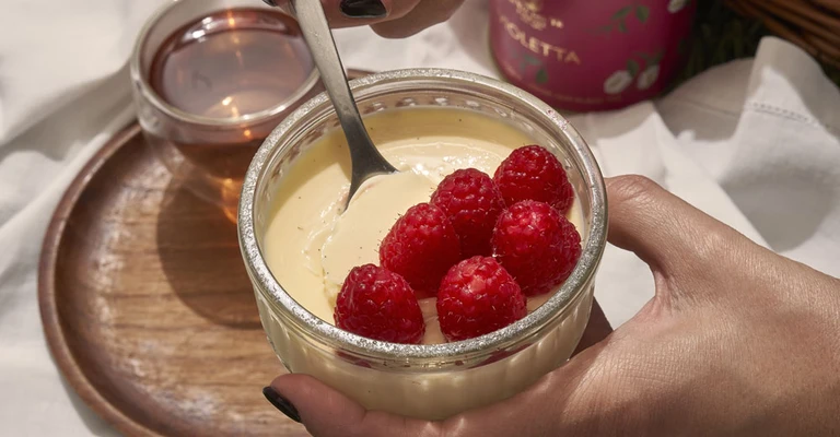 Detail of with hand aggiunge raspberries fresh sopra with creamy dessert servito in with bowl on tray.