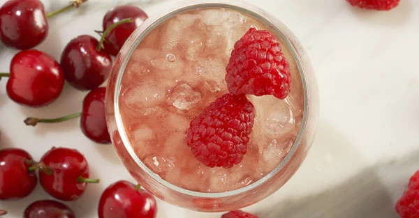 Close-up of pink cocktail with citrus fruits and cherries.