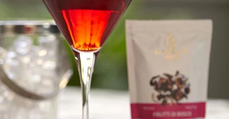 Close-up of red cocktail with package and ingredients.