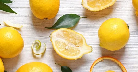 Composition with lemons interi and tagliati arranged on with background light.
