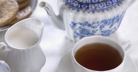 Close-up of cup of tea with teapot blue decorated.