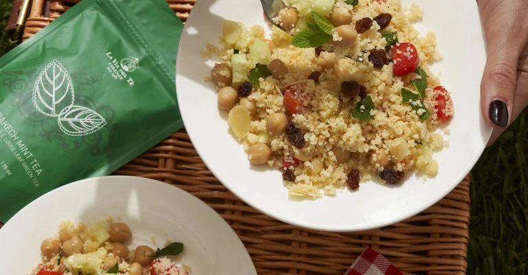 Scena of picnic outdoors with picnic with plate of pasta and bag green.