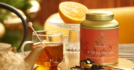 Close-up of tea jar with honey and citrus fruits outdoors.