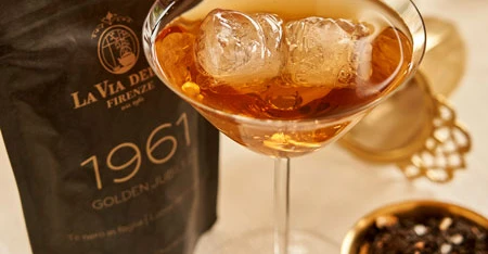 Gros plan de cocktail avec sachet noire 1961 et feuilles de thé.