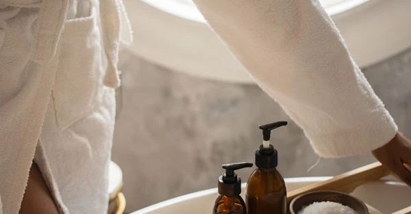 Angolo benessere con lavabo, candele accese, asciugamani e oggetti da cura del corpo, illuminato da luce calda.