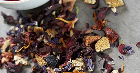 Primo piano di miscela di frutta e fiori essiccati, ripreso da vicino per mostrarne consistenza, colore e forma su fondo chiaro o naturale.